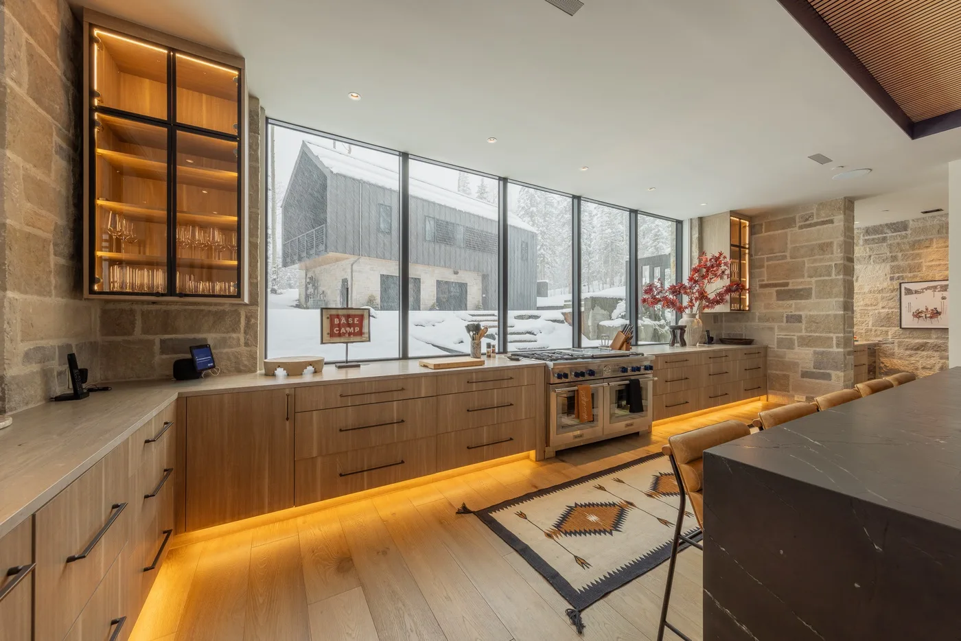 A modern kitchen with wood cabinetry, a central island, and large windows.