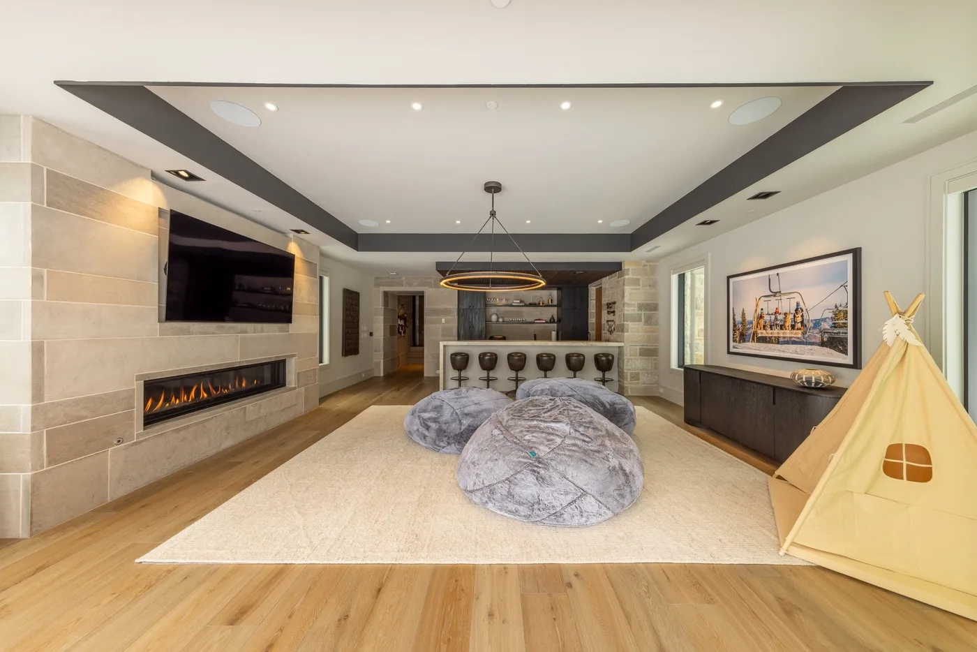 A modern living room with a large rug, low seating, and a wall-mounted television.