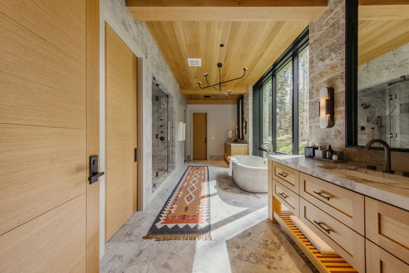 A spacious bathroom with a freestanding bathtub, glass shower, and long vanity.