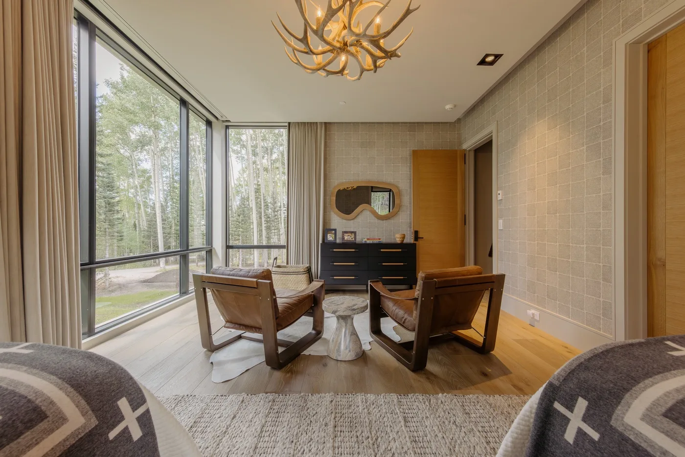 A sitting area with two armchairs and large windows overlooking trees.