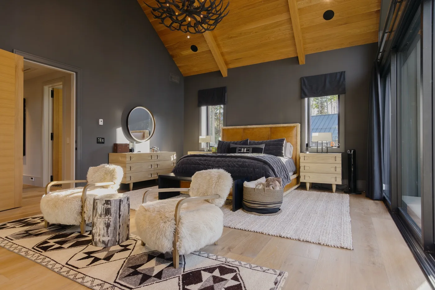 A bedroom with a bed, light wood furnishings, and a seating area.