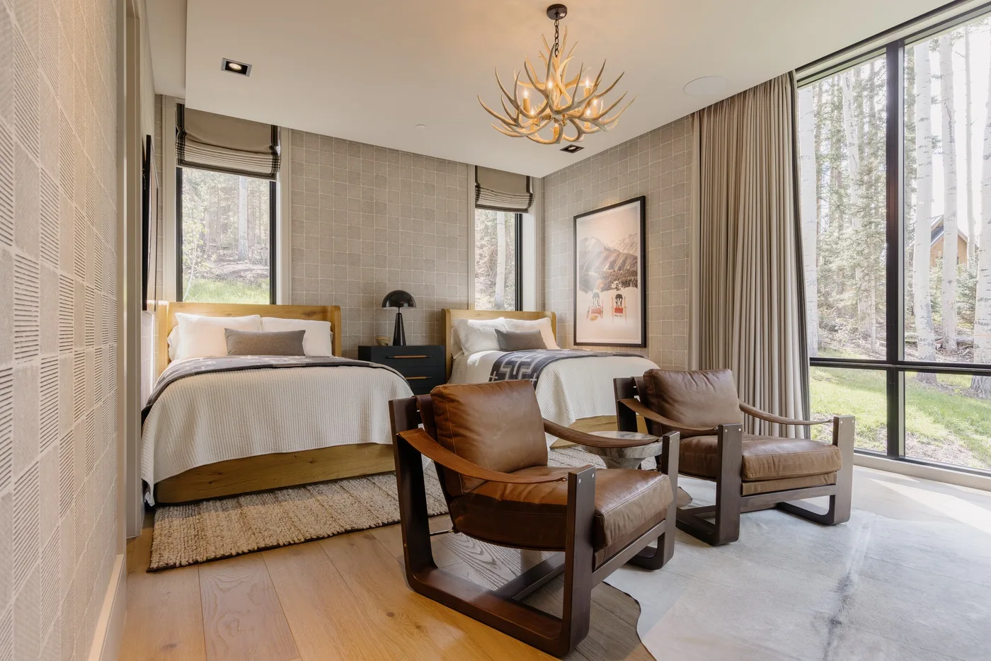 A bedroom with two beds and seating beside large windows.