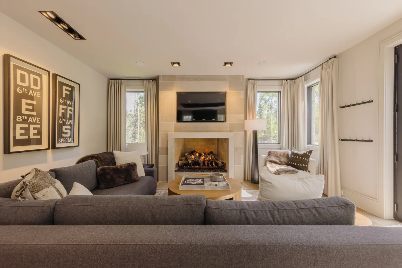 A bright living room with seating arranged around a fireplace and television.