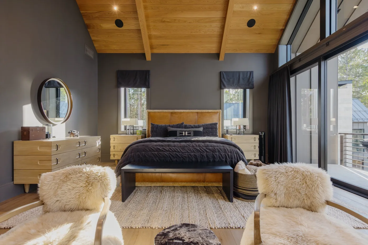 A bedroom with a large bed, bedside tables, and tall windows.
