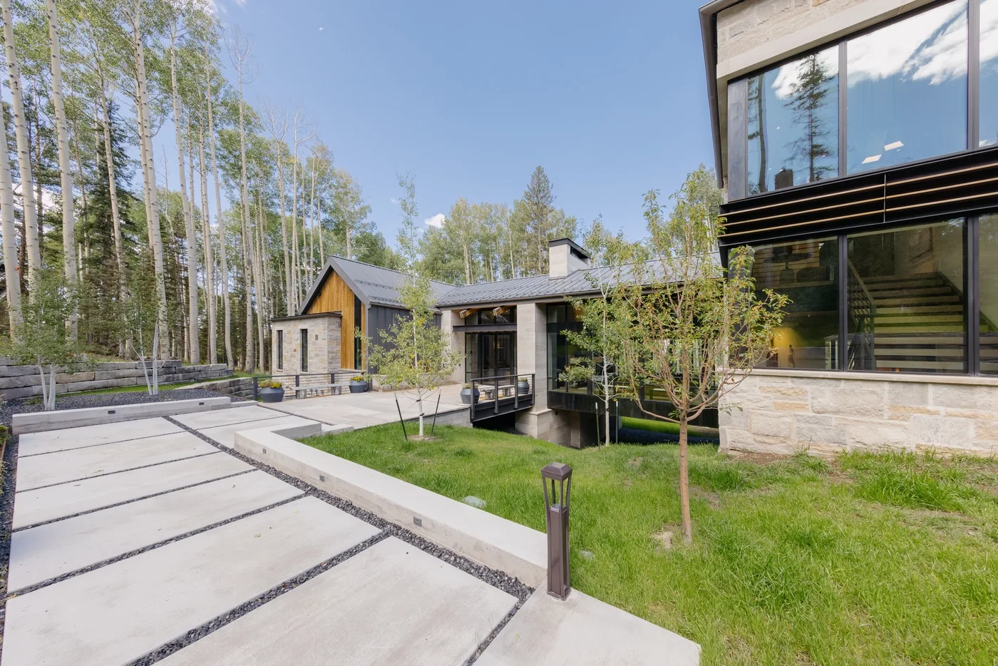 A modern house beside a paved driveway and landscaped lawn.