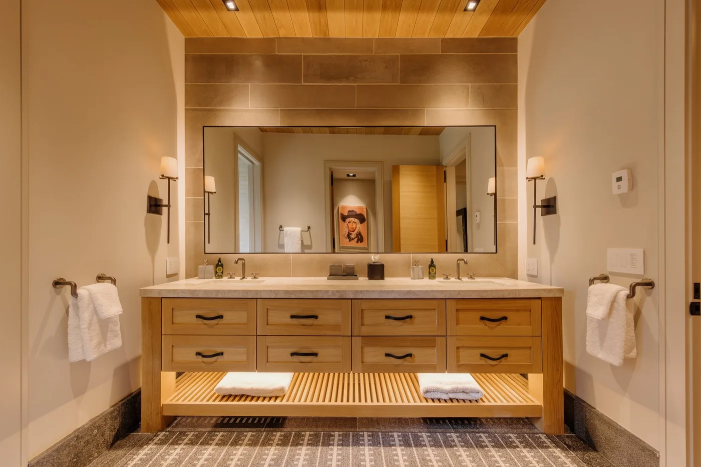 A bathroom vanity with a wide mirror and warm wood cabinetry.