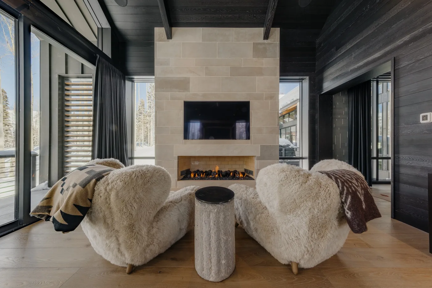 A living room with plush seating facing a fireplace and television.