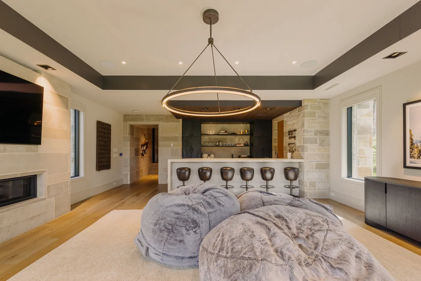 A spacious living room with plush seating, a bar counter, and a hanging ceiling light.
