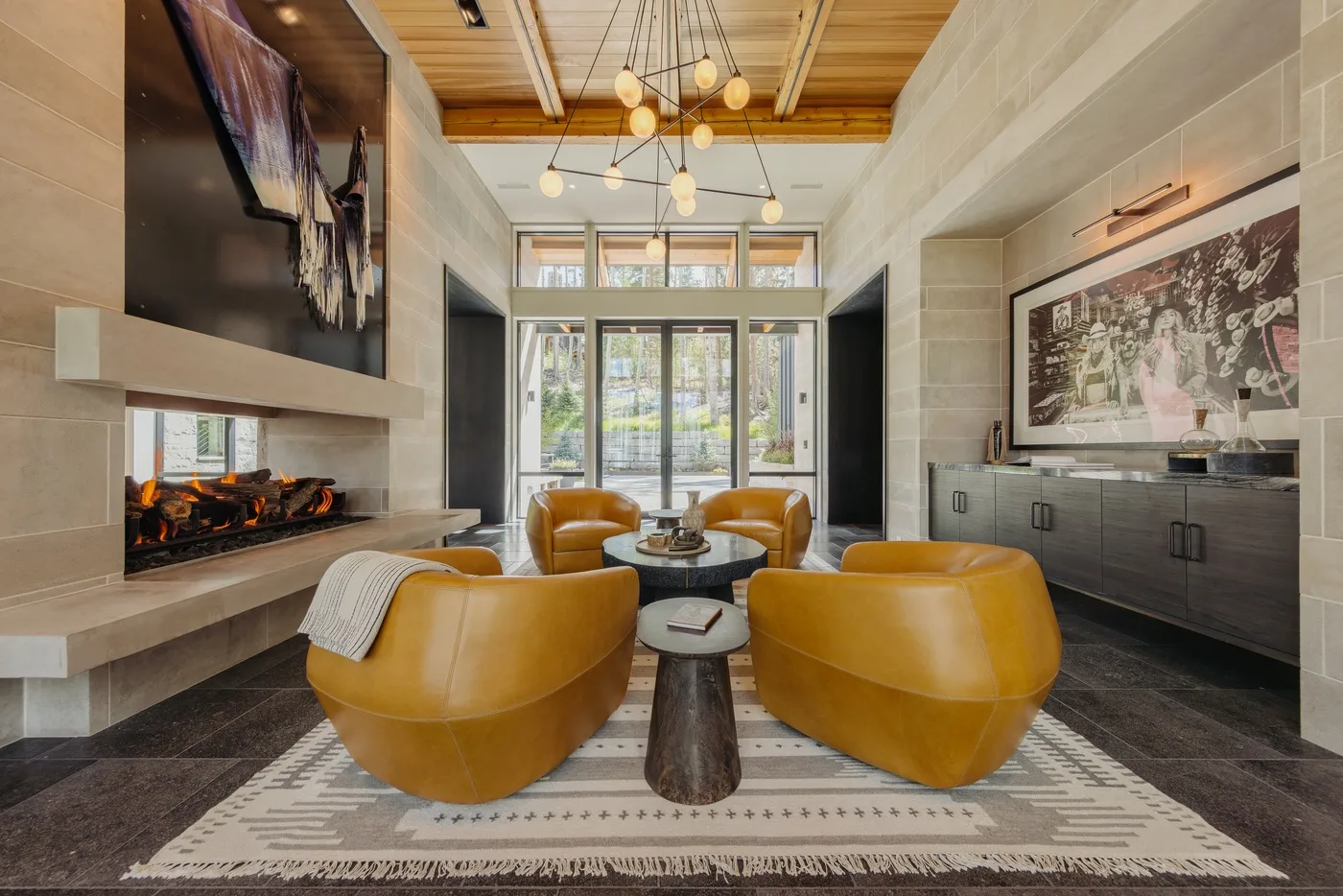 A modern living room with curved seating arranged around a low table beside a fireplace.