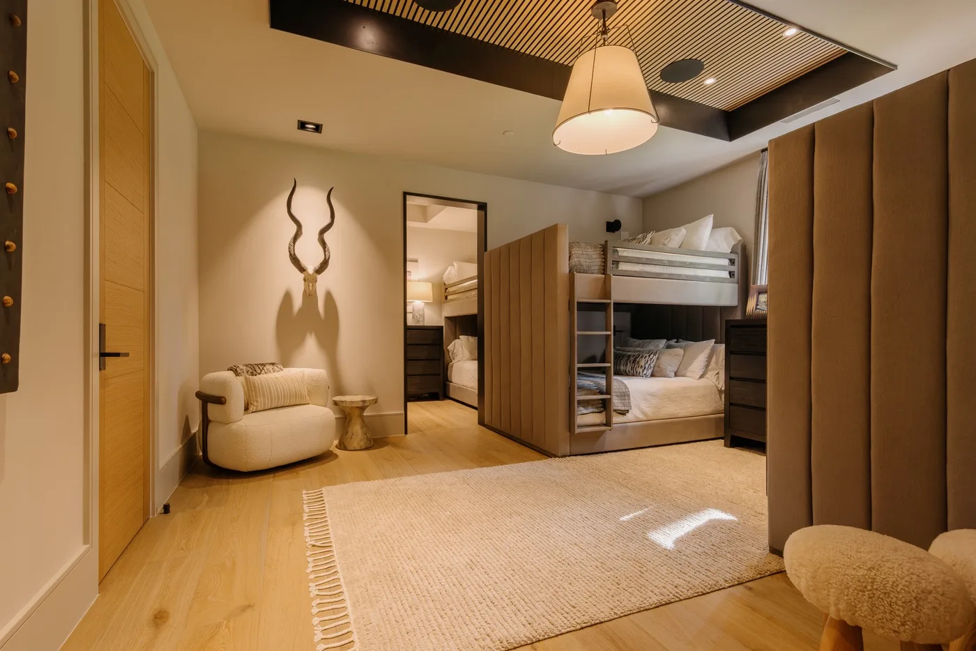 A bedroom with a bunk bed, a lounge chair, and a large area rug.