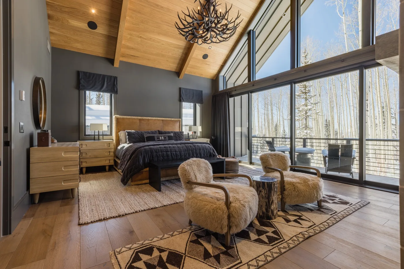 A bedroom with a bed and seating beside floor-to-ceiling windows.