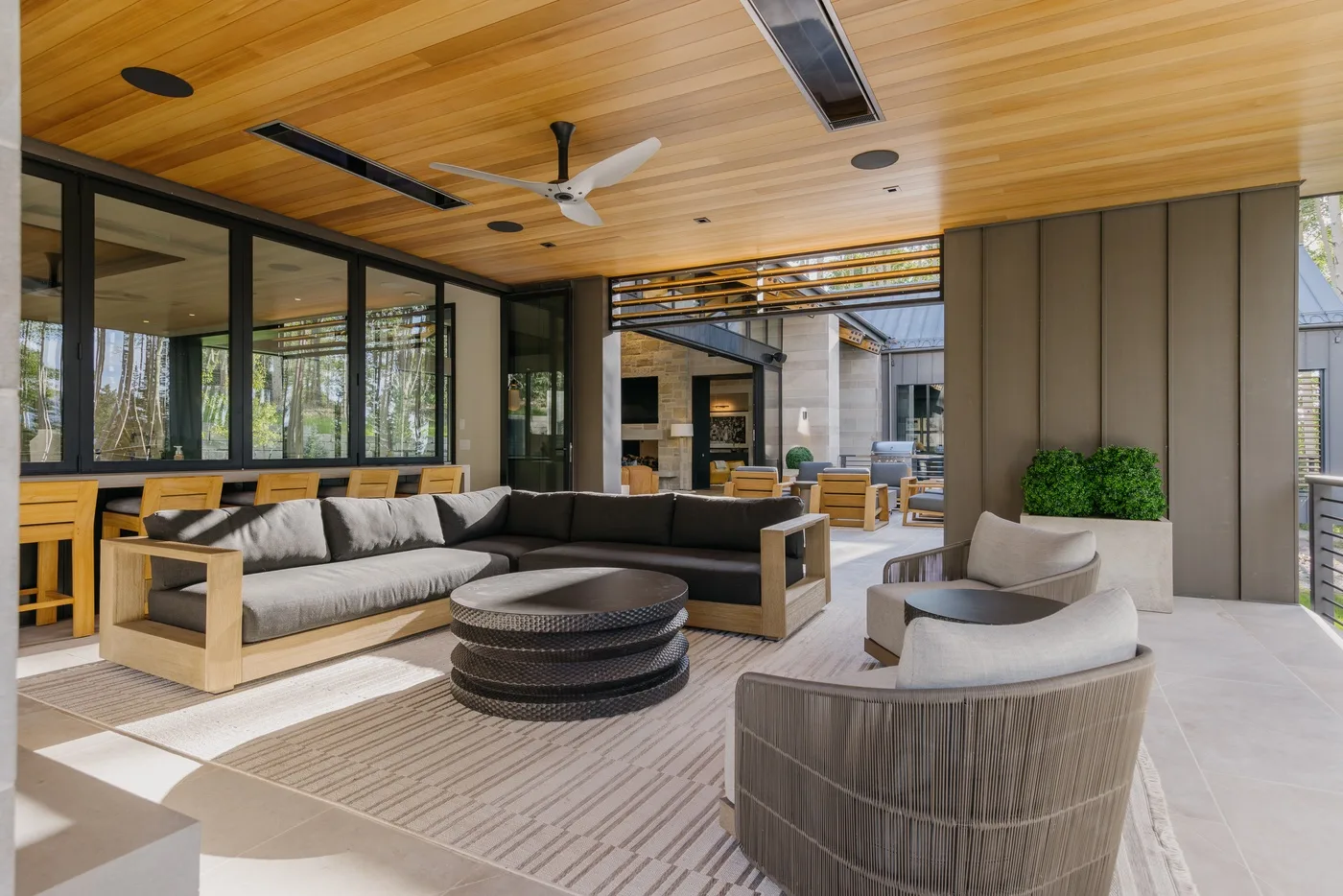 A covered lounge with seating arranged around low tables beneath a wood-paneled ceiling.