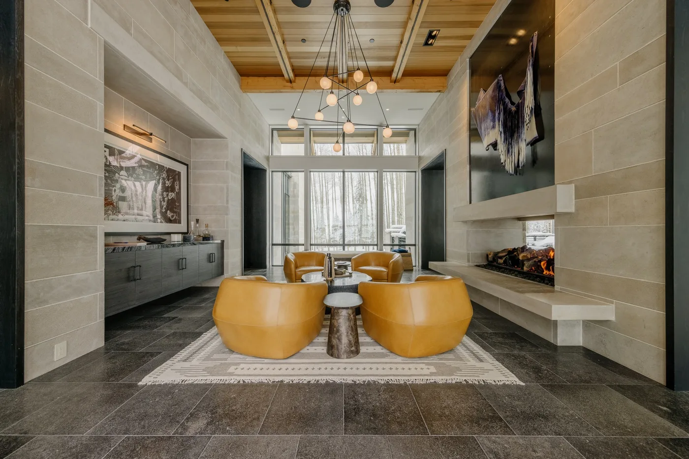 A modern living room with curved seating, a central fireplace, and large windows.