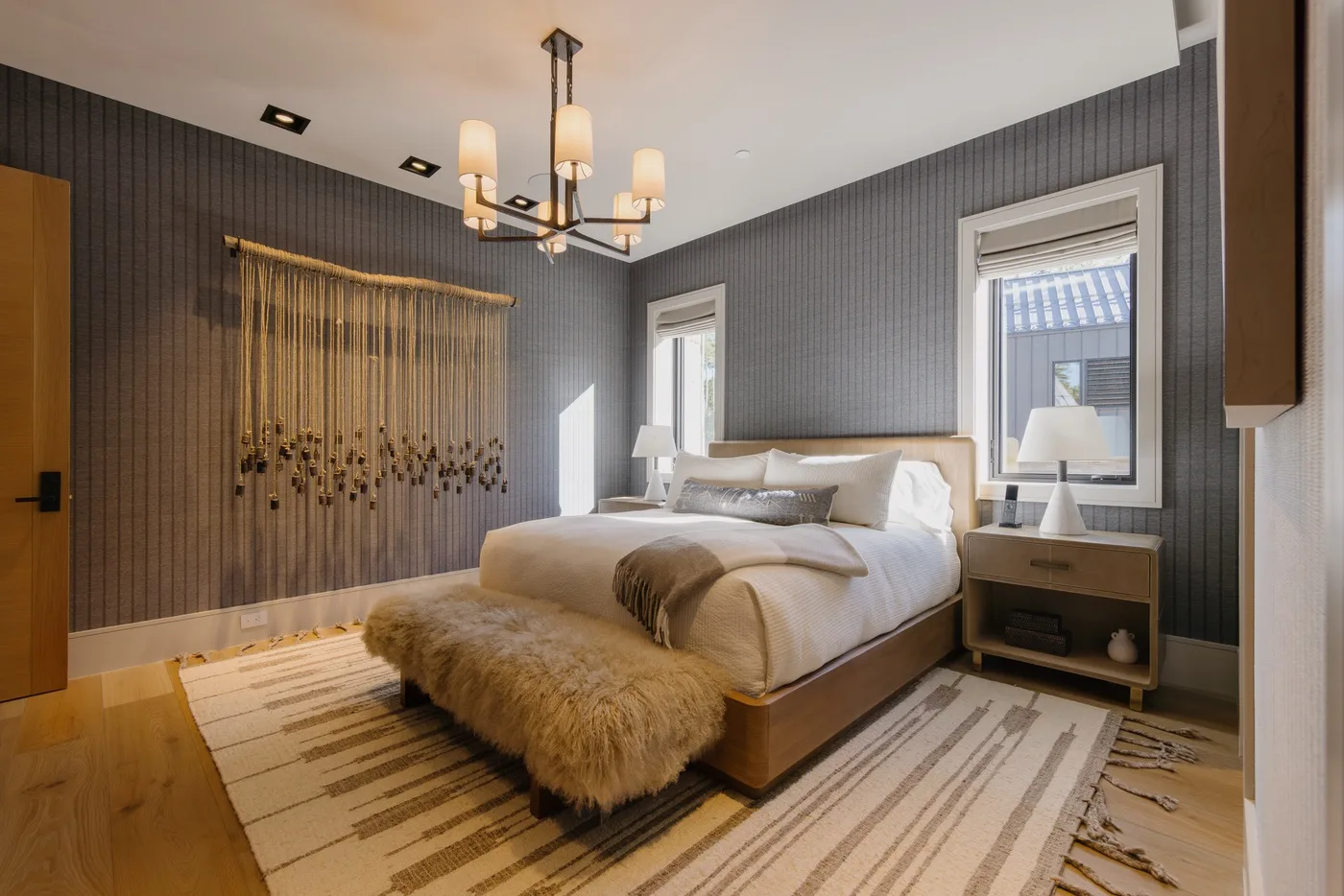 A bedroom with a neatly made bed, bedside tables, and a chandelier.