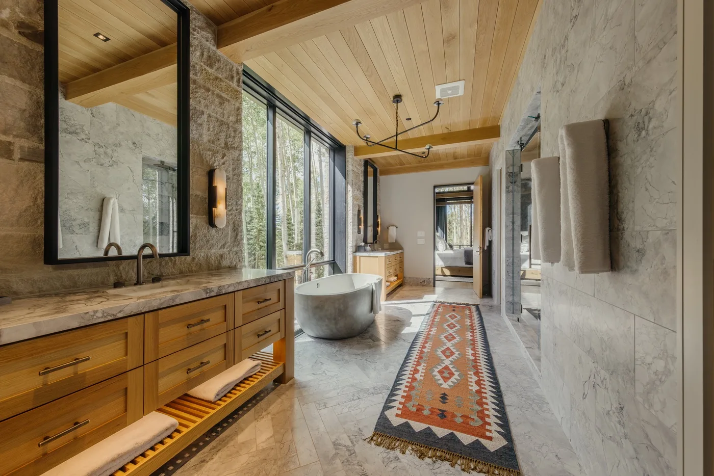 A spacious bathroom with a freestanding tub, long vanity, and patterned runner.