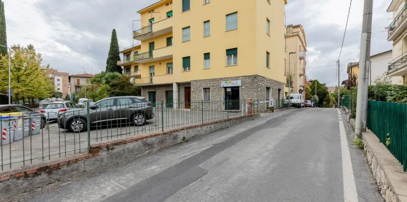 Una calle pavimentada pasa junto a un edificio de apartamentos amarillo y coches estacionados.
