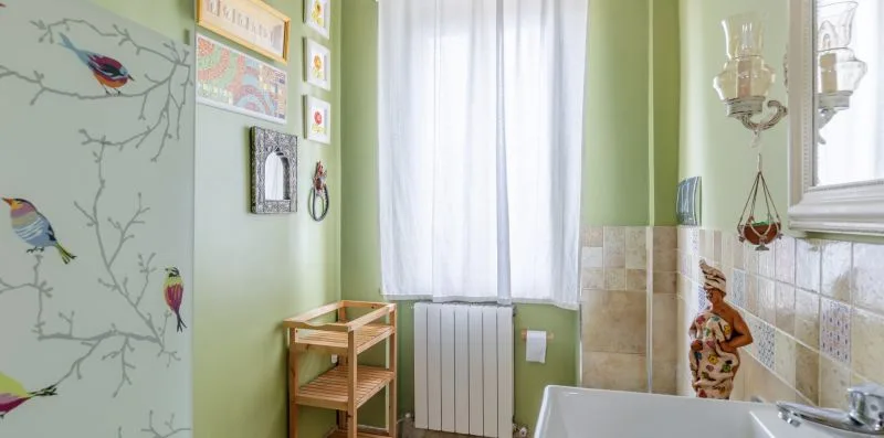 Un baño verde con bañera, paredes alicatadas y una ventana luminosa.