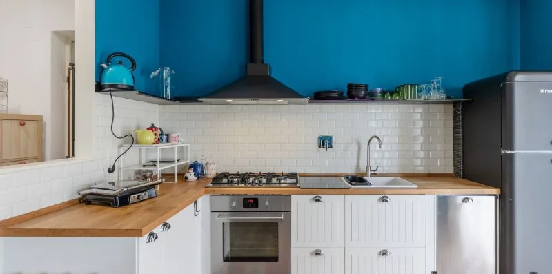 Una cocina con gabinetes blancos, encimeras de madera y un refrigerador de acero inoxidable.