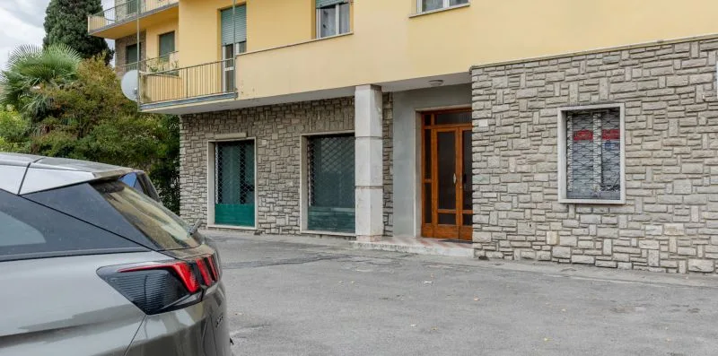 Entrada de un edificio con una puerta de madera y paredes exteriores con acabado de piedra.