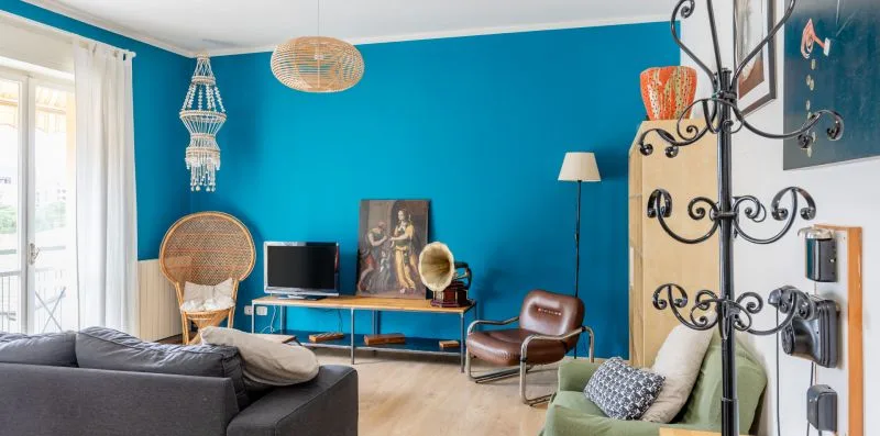 Una sala luminosa con paredes azules, asientos y un televisor.