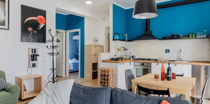 Una sala de estar y cocina de concepto abierto, con paredes azules y una mesa de comedor.