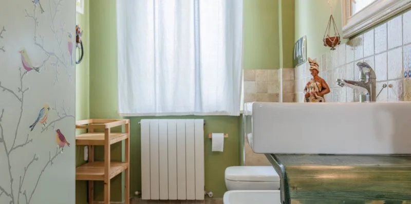 Un baño con bañera, lavabo y ventana con cortinas translúcidas.