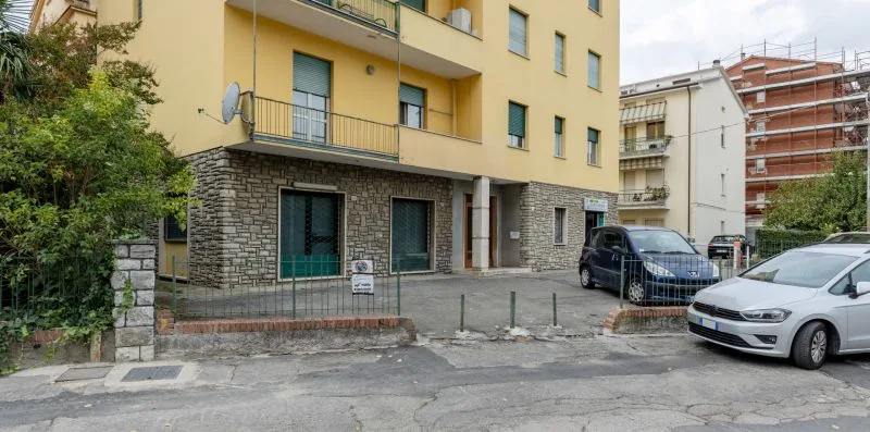 Un edificio de apartamentos amarillo con paredes exteriores de piedra y coches estacionados en la calle.