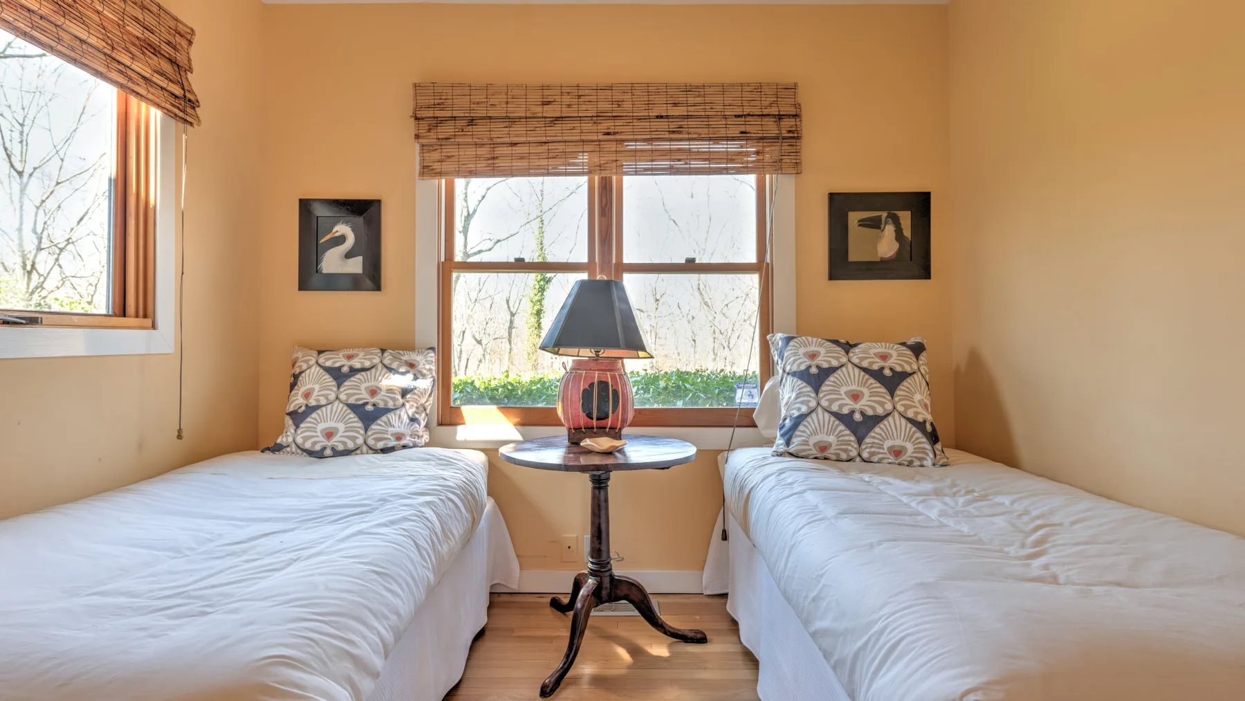 A bedroom with two single beds beside a central window and bedside table.