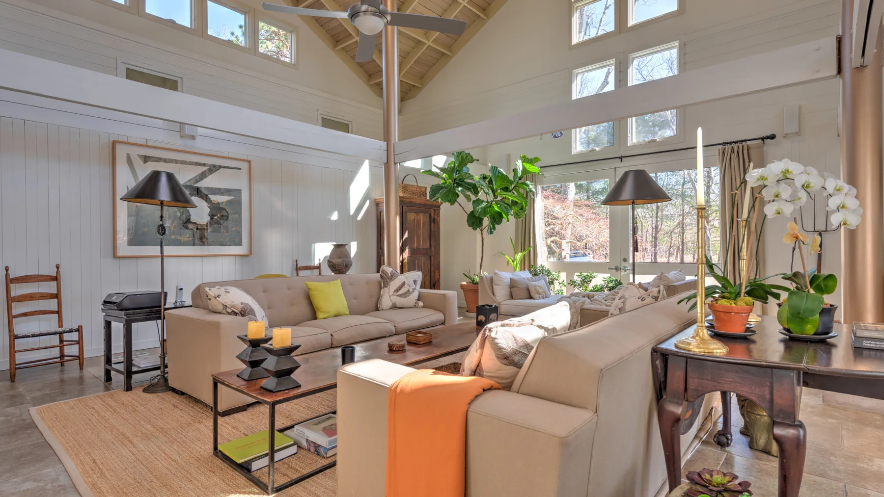 A bright living room with sofas, a coffee table, and large windows.