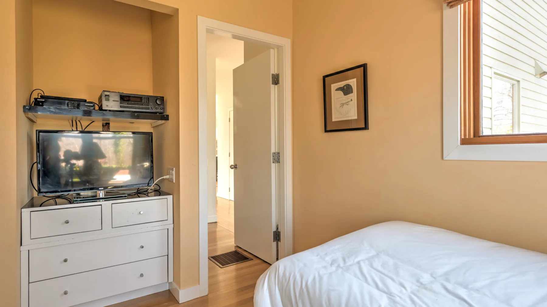 A bedroom with a bed, a dresser, and an open doorway.