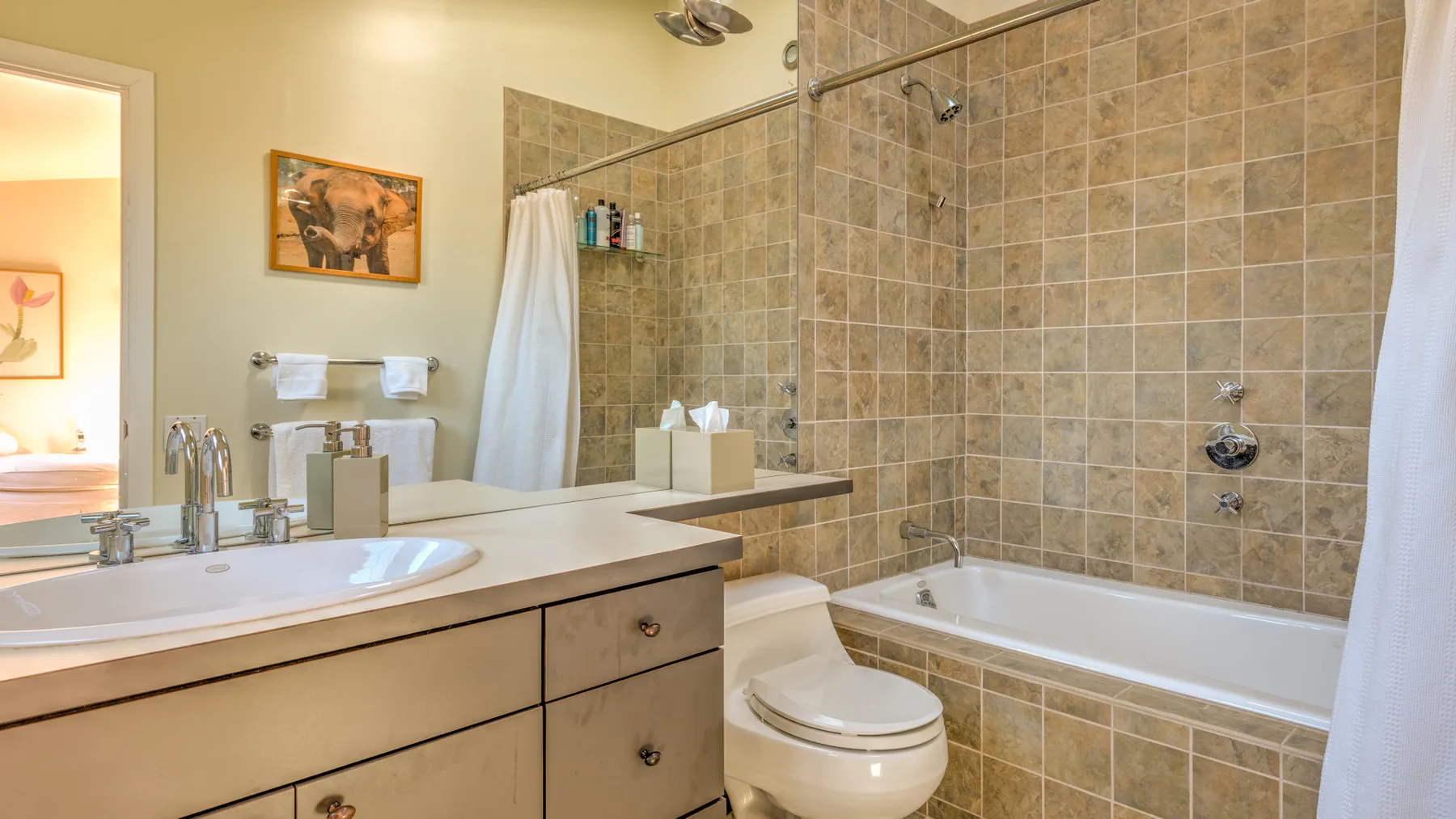 A bathroom with a vanity, toilet, and bathtub beside a tiled shower area.