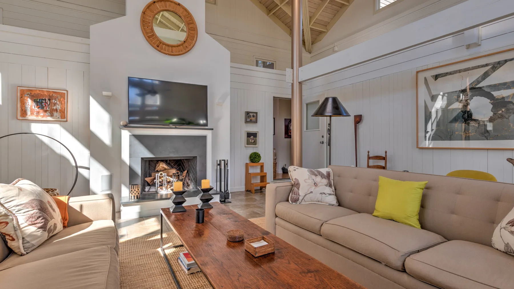 A bright living room with a fireplace, television, and seating around a wooden coffee table.