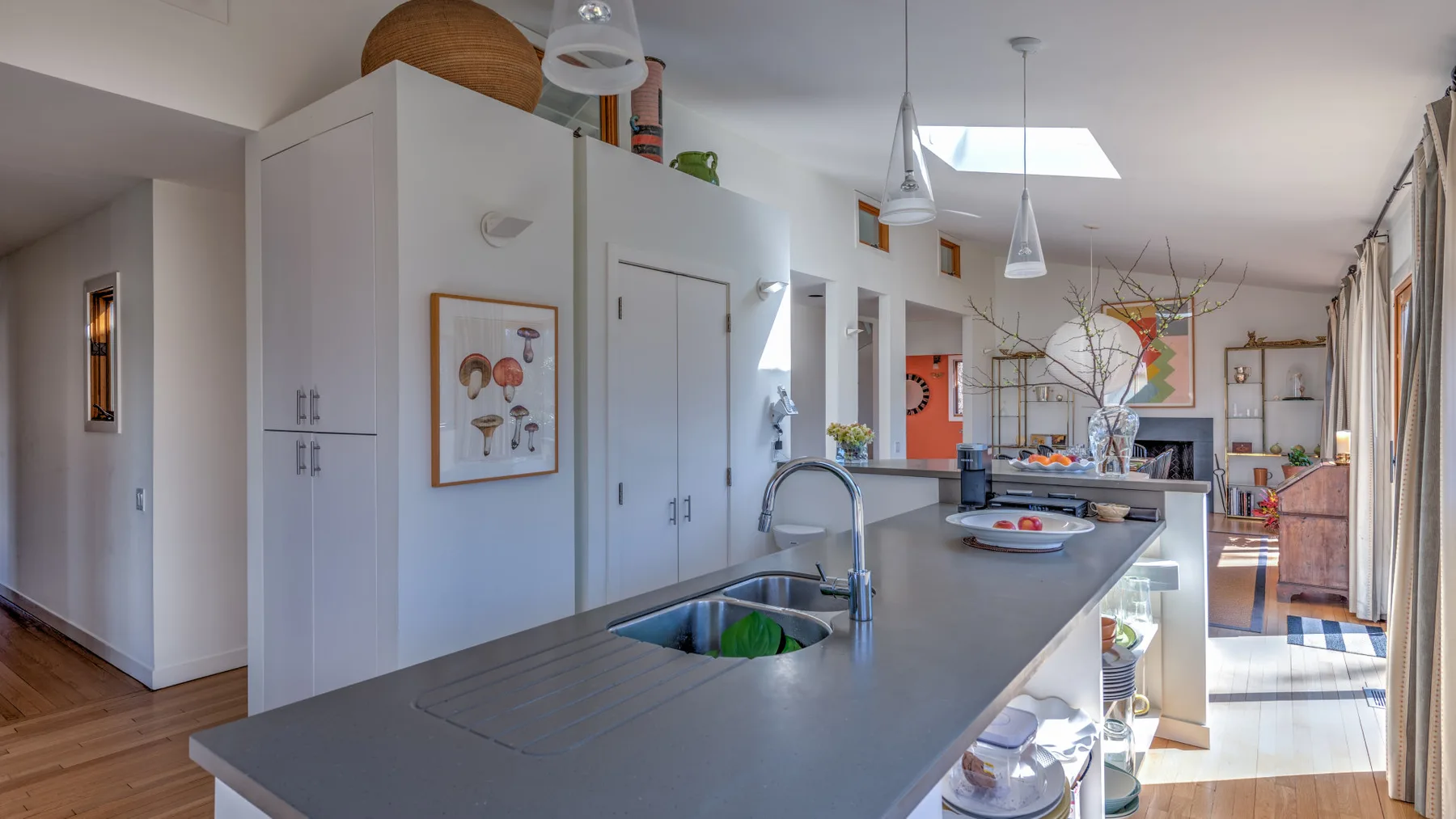 Una cocina luminosa con una isla larga, fregadero y lámparas colgantes.