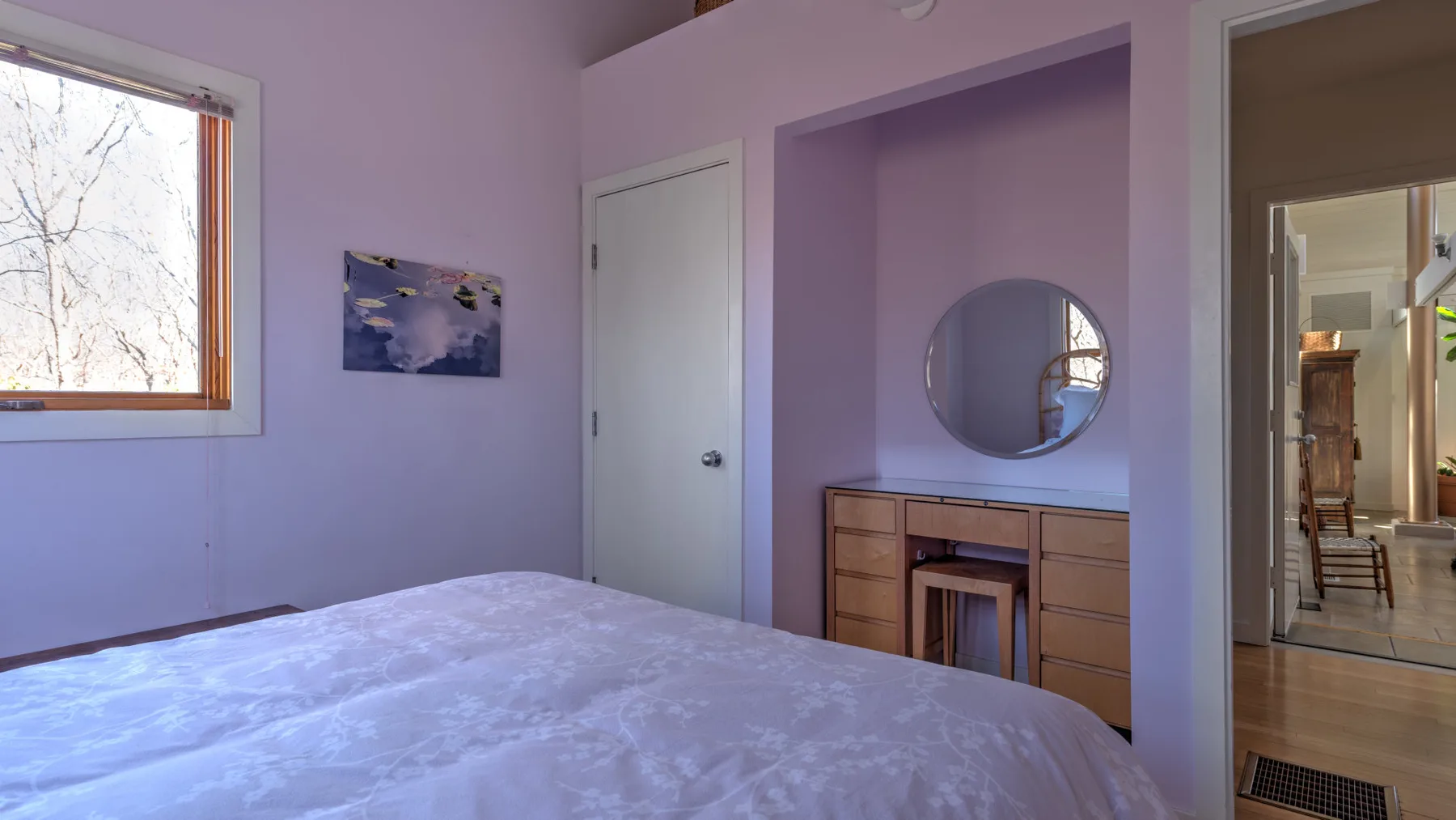 A bedroom with a bed, a window, and a recessed dressing table.
