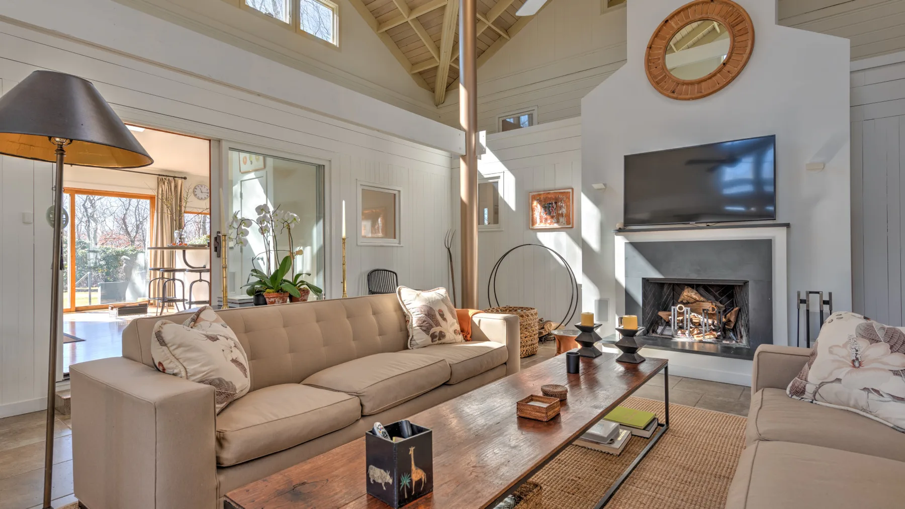 A bright living room with seating arranged around a coffee table and fireplace.