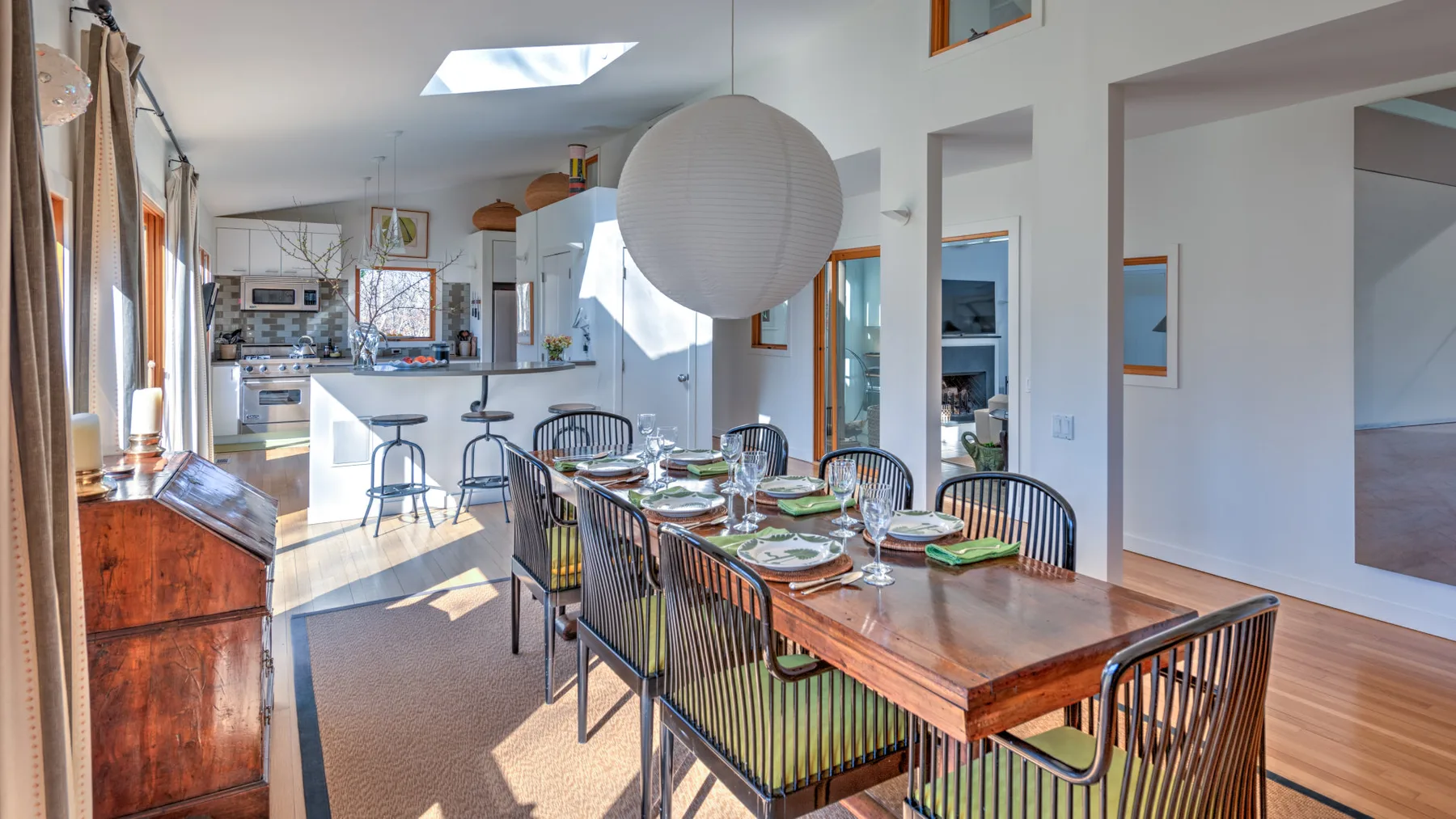 A dining area with a long wooden table set with dishes and chairs.