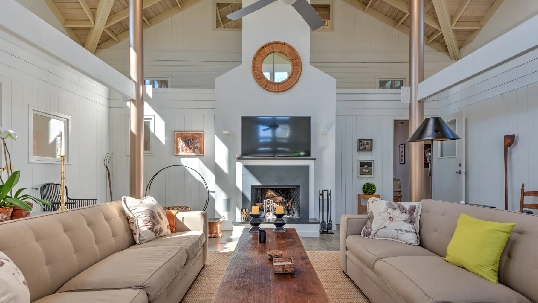 A bright living room with seating arranged around a central fireplace and coffee table.