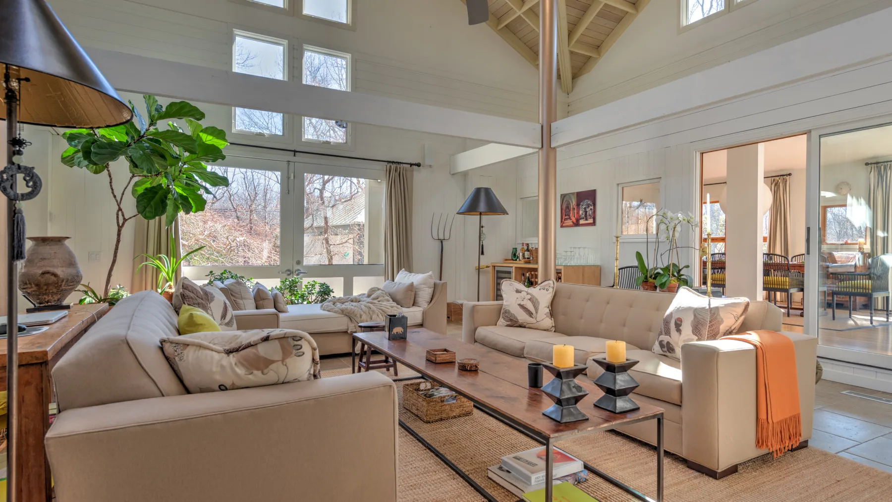 A bright living room with large windows and seating around a coffee table.