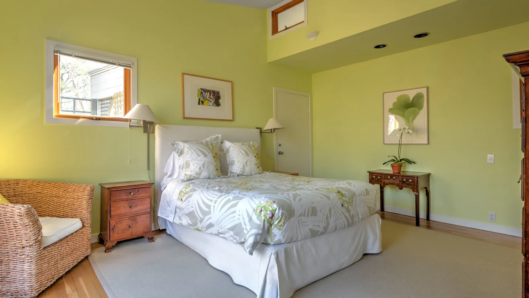 A bedroom with a bed, bedside tables, and a wicker chair.