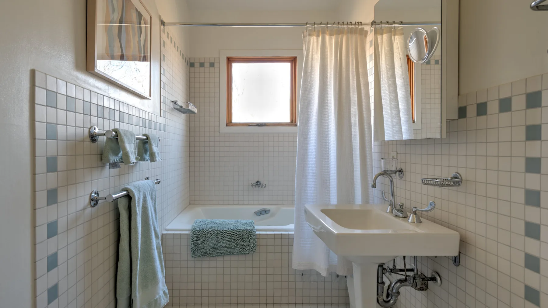 A tiled bathroom with a bathtub, shower curtain, and sink.