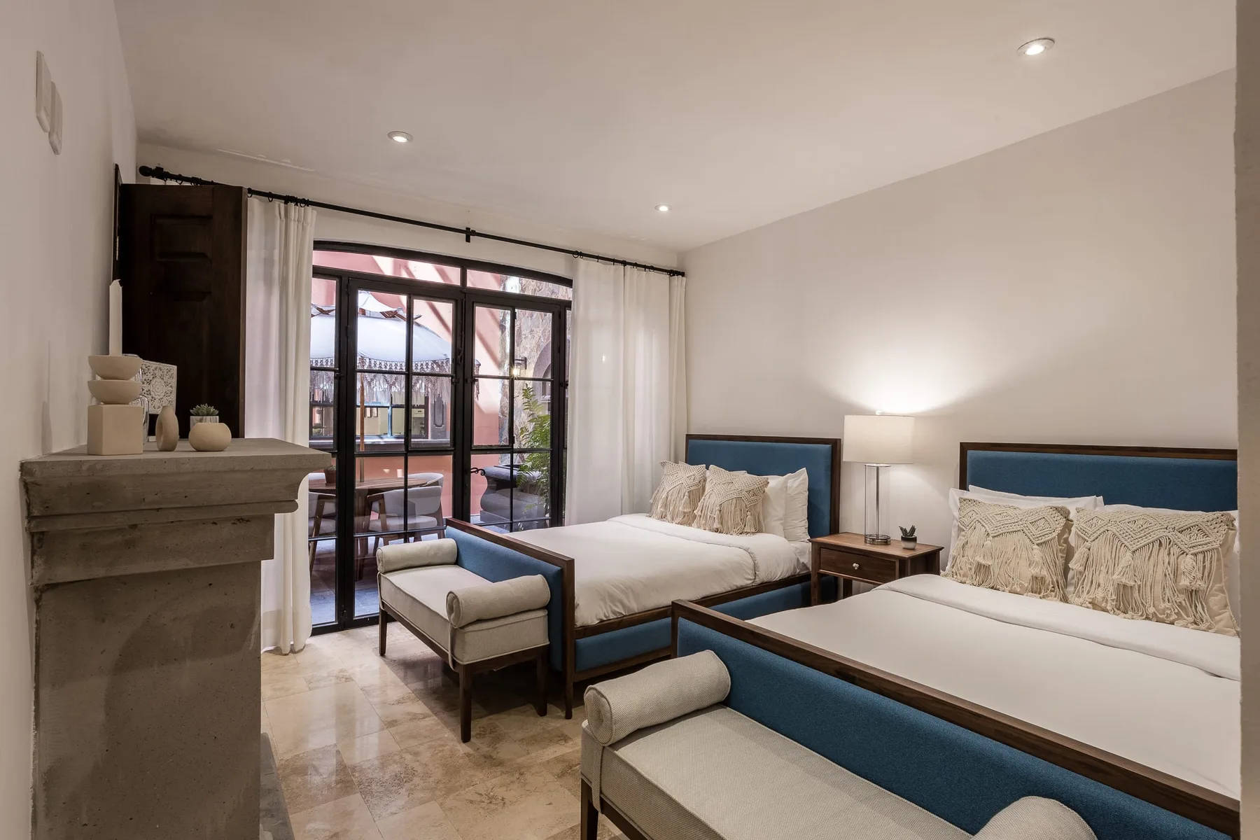 A bedroom with two beds and a seating area beside glass doors.