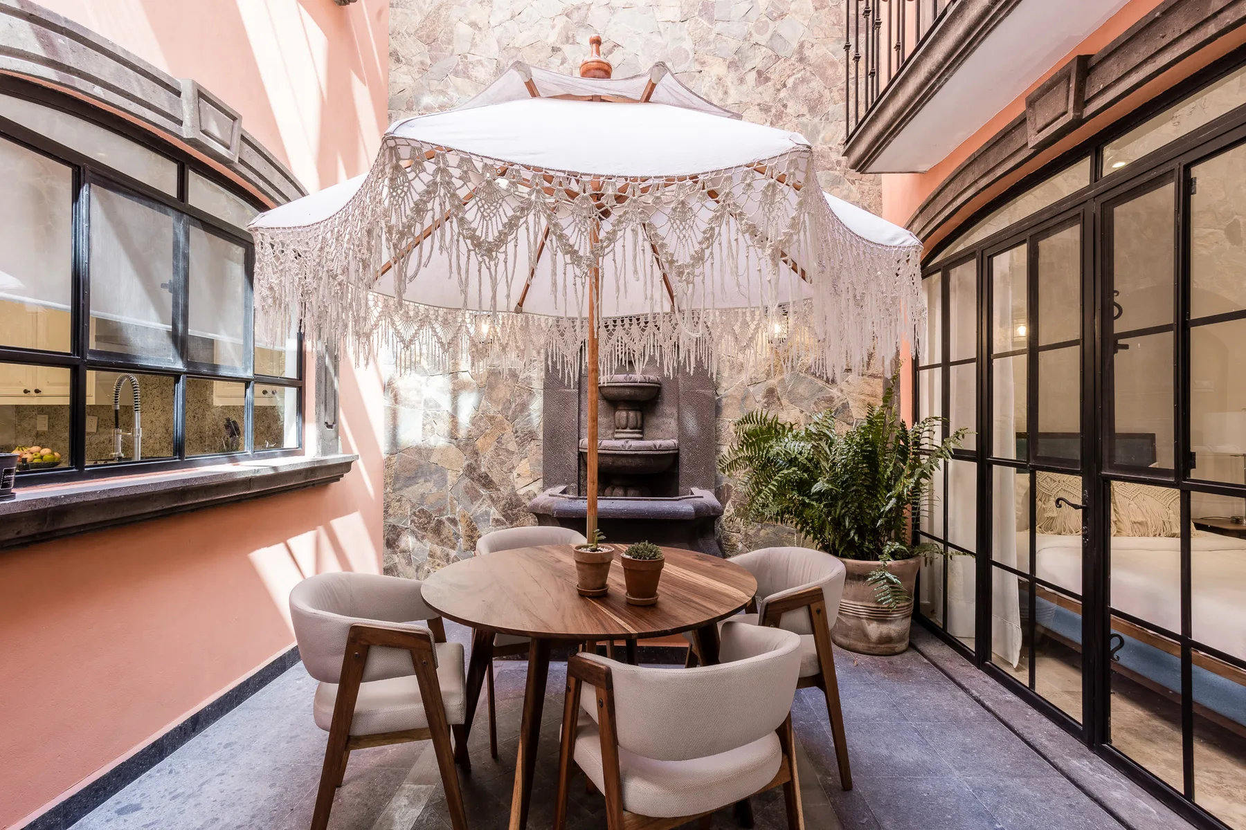 A bright indoor dining area with a round table beneath a fringed canopy.
