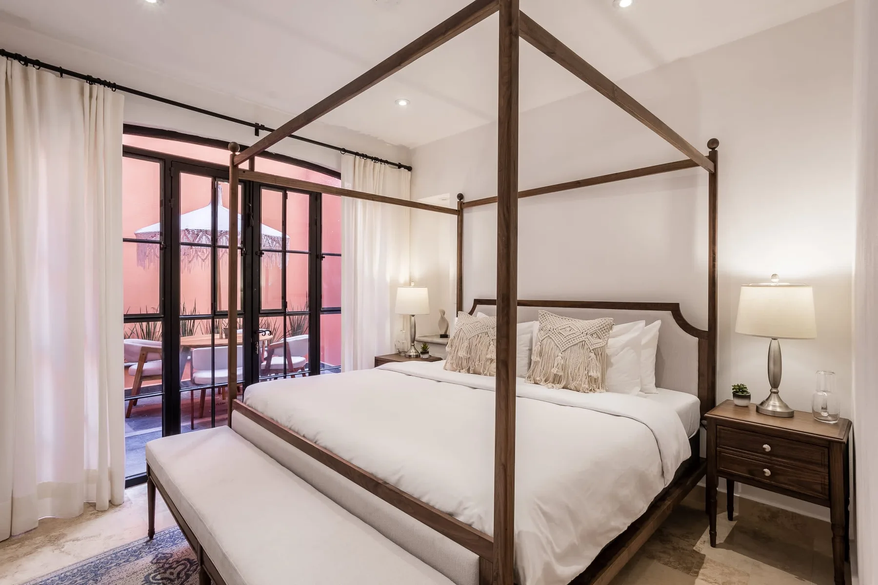 A bedroom with a four-poster bed and glass doors opening to a balcony.
