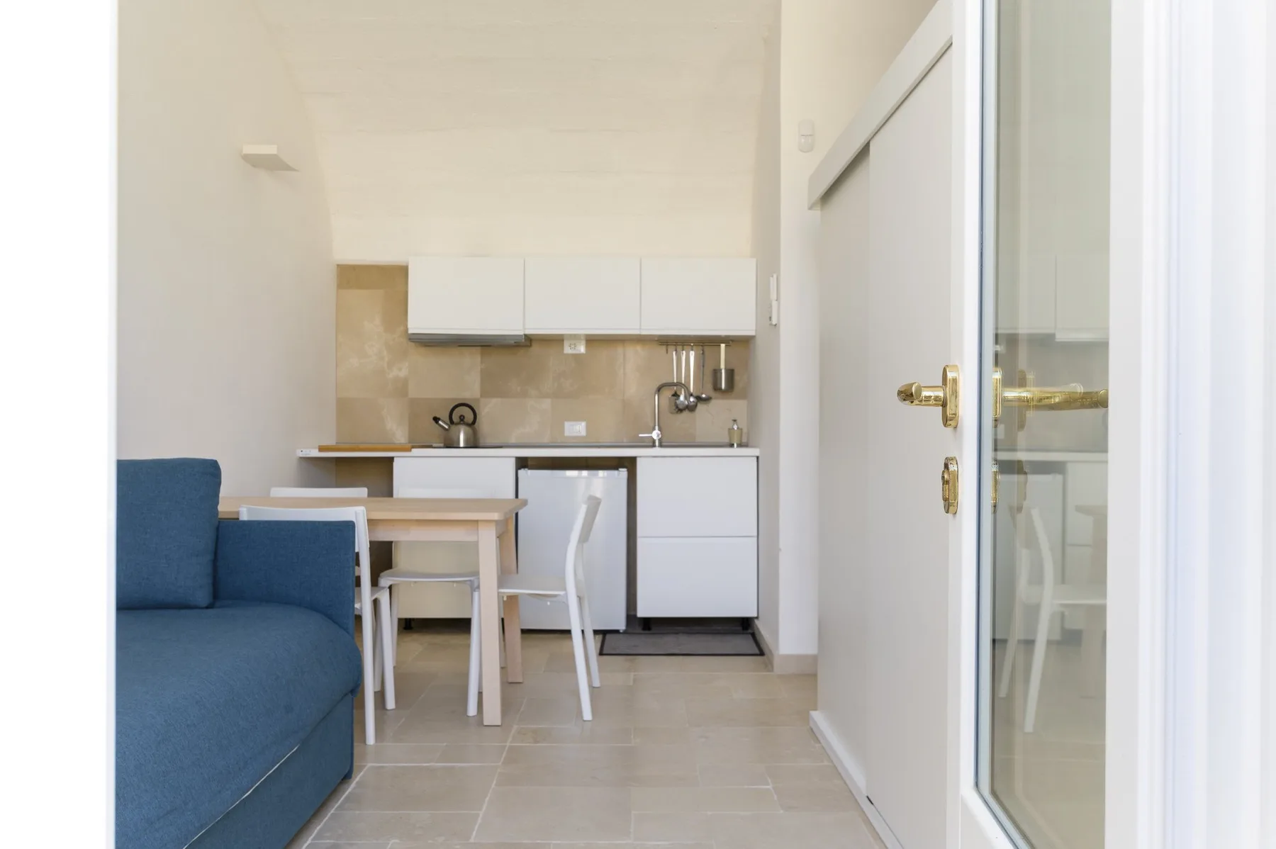 A compact kitchen and dining area with blue seating beside a glass door.