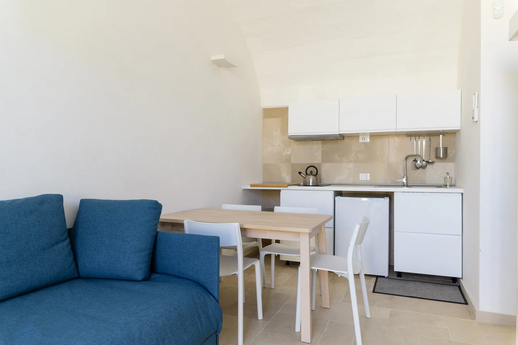Una cocina compacta y zona de comedor con asientos azules en primer plano.