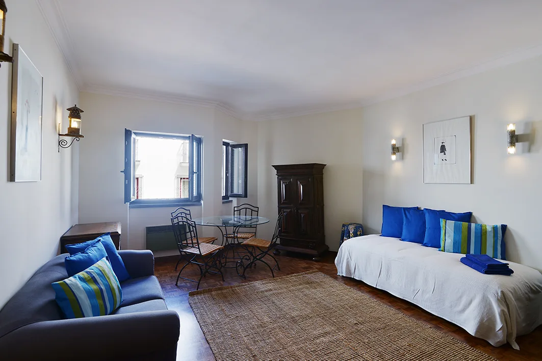 Una sala de estar con asientos alrededor de una mesa pequeña y un diván junto a la pared.