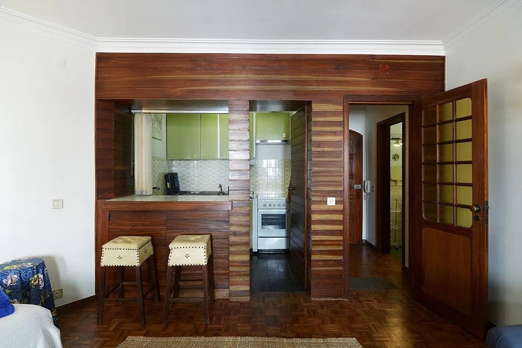 Una zona de cocina compacta se abre a un interior con suelo de madera.