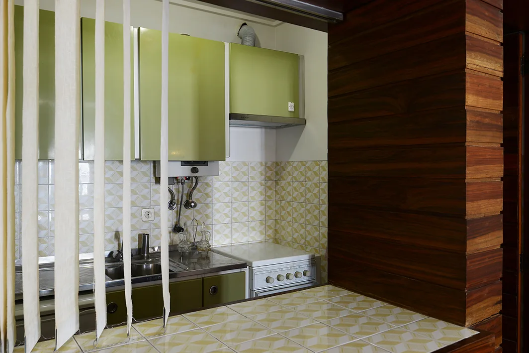 A compact kitchen with green cabinets, a tiled counter, and a cooktop.
