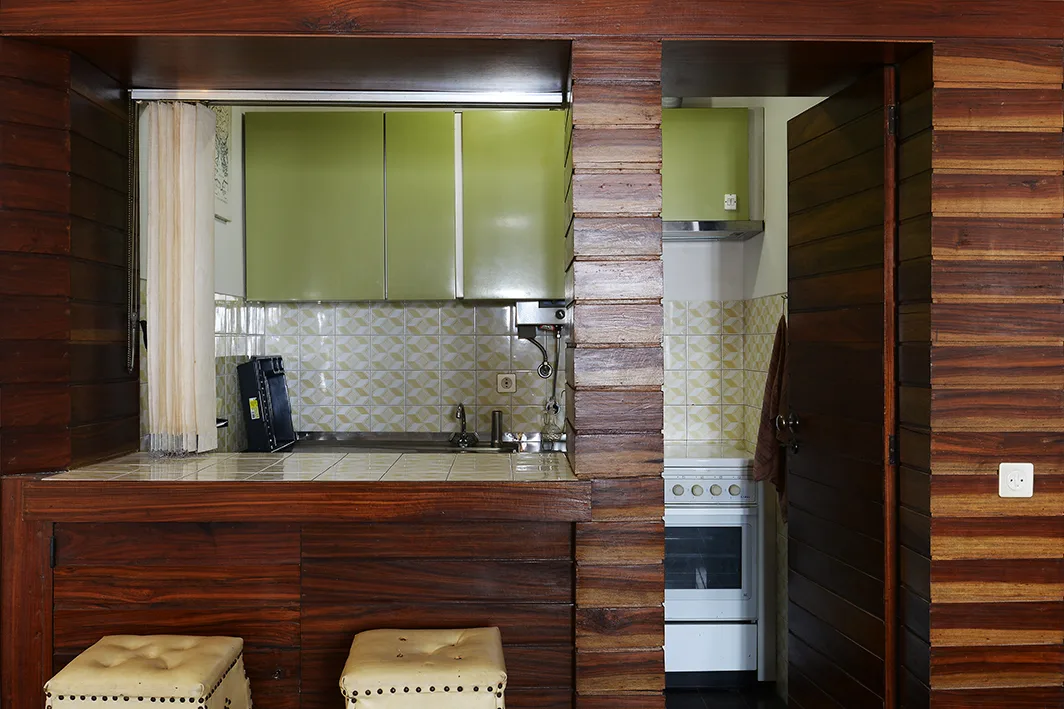 Una cocina compacta con armarios verdes y un horno integrado.