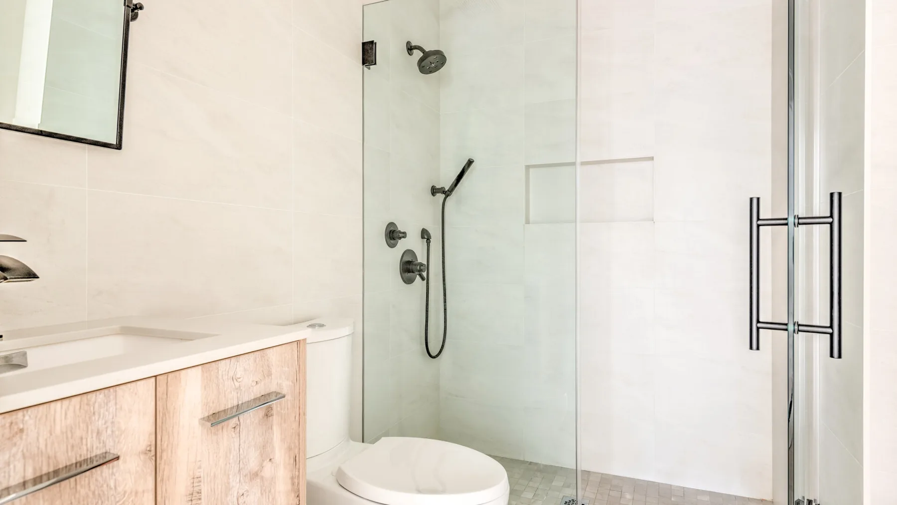 Un baño luminoso con una ducha de vidrio y un mueble de lavabo.